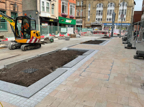 A photo of the rain gardens and completed paving on King Street. The road is still unfinished with a construction digger on it.