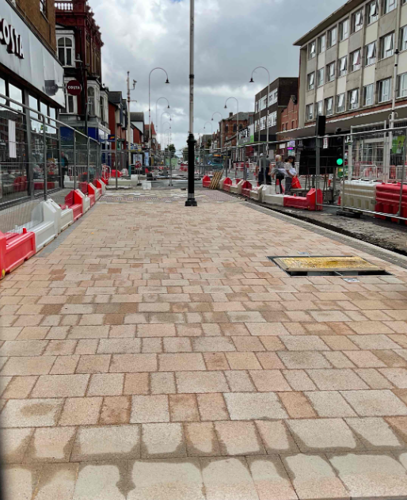 A photo of the fresh new orange/pink paving tiles on Eastbank Street outside Costa. There is a lighting column by the crossing.