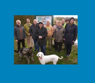 Cllr Liz Dowd and members of Rimrose Valley Friends group and their dogs stood in front of a park notice board