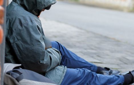 Homeless person sitting on pavement
