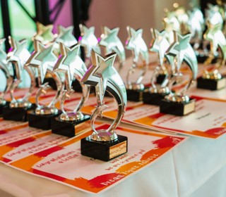 Star shaped Superstar Awards  lined up on a table, standing  on top of  orange certificates