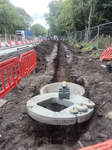 A long trench has been dug and a round concrete drainage hole has been put in the end. The trench looks ready for a pipe.